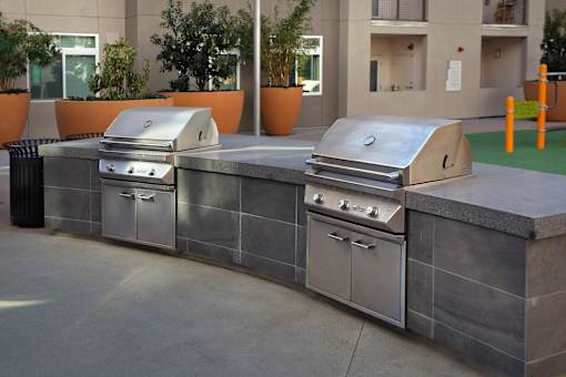 A set of outdoor grills are on a concrete slab.