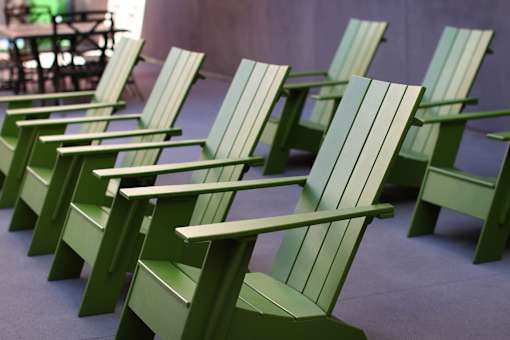 A row of green wooden chairs are lined up in a row.