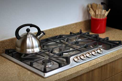A silver kettle is on a gas stove.