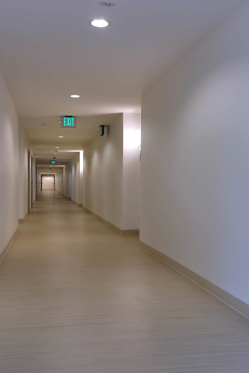 A long hallway with exit sign on the wall.