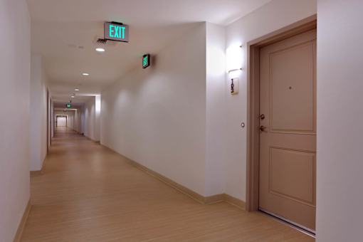 A long hallway with a green exit sign.
