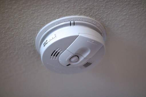 A smoke detector is mounted on a white wall.