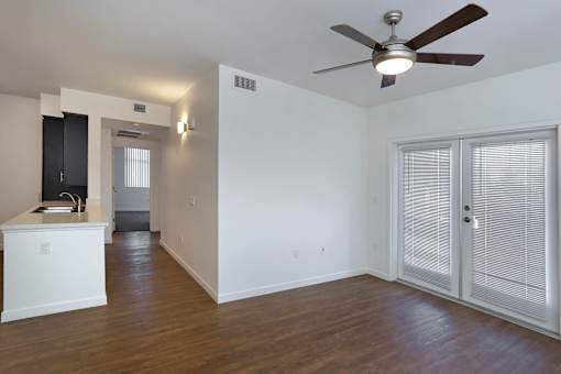 A room with a ceiling fan and a white cabinet with a black monitor.
