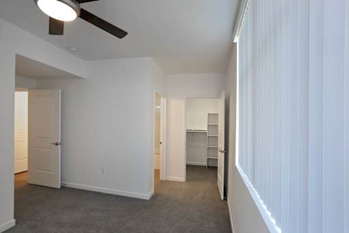 A room with a ceiling fan and white walls.
