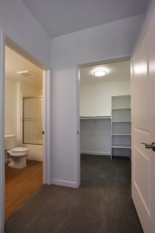 A white door is open to a bathroom with a toilet and a vanity.
