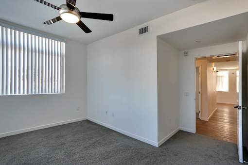 A room with a ceiling fan and a window with blinds.