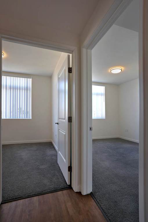 A hallway with a carpeted floor and white walls.