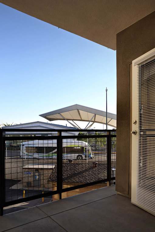 A white umbrella is on a patio over a black railing.