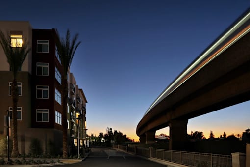 A street with a bridge and a building with palm trees.