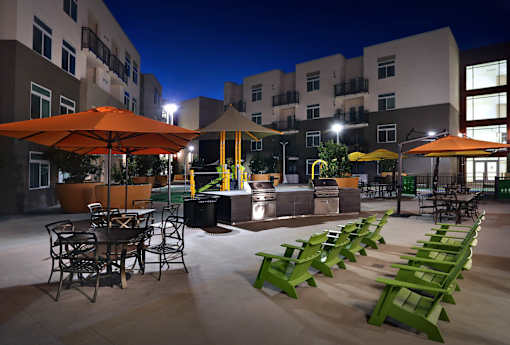 A patio area with tables and chairs is lit up at night.