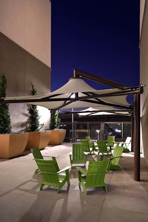 A patio with green chairs and a white umbrella.