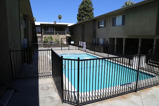 A black fence surrounds a small pool in a courtyard.