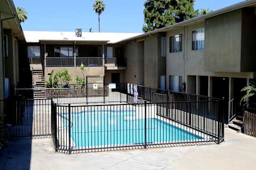 A black fence surrounds a small pool in a courtyard.