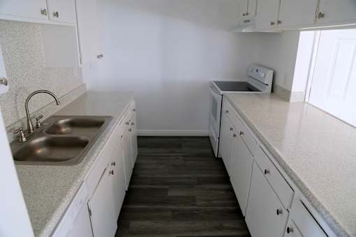 A kitchen with white cabinets and a wooden floor.