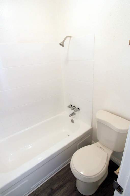 A white toilet sits next to a bathtub in a bathroom.
