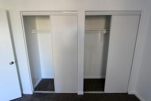 Two white closet doors in a room.