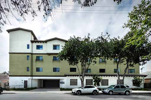 A white and beige building with a parking lot in front.