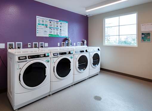A row of white washing machines in a laundromat.