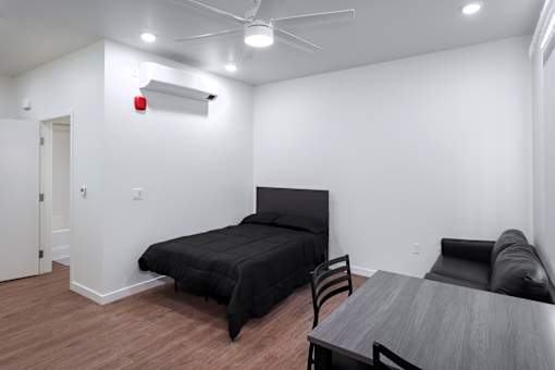A bedroom with a bed, chair, and table.