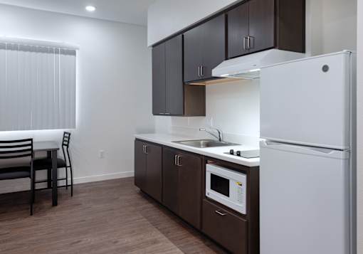 A kitchen with a white refrigerator, brown cabinets, and a white countertop.