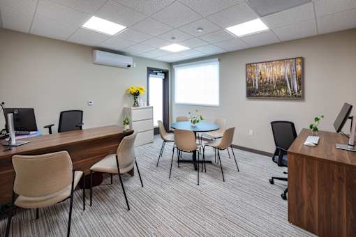 A conference room with a long table and chairs, a vase of flowers, and a painting on the wall.