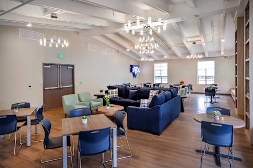 A room with a blue couch, chairs, and tables.