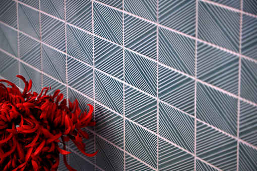 A red flower sits in front of a grey and white patterned background.