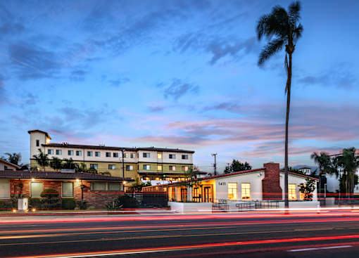 A building with a palm tree in front of it at dusk.