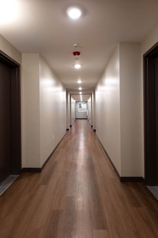 A long hallway with wooden floors and white walls.