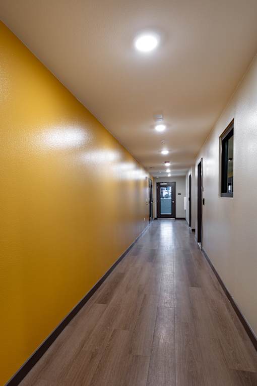 A long hallway with wood floors and yellow walls.