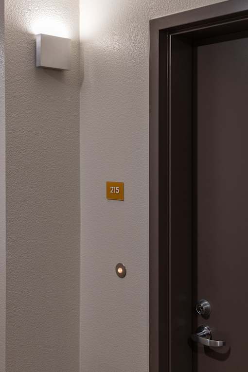 A brown door with a silver handle and a number 215 on the wall.