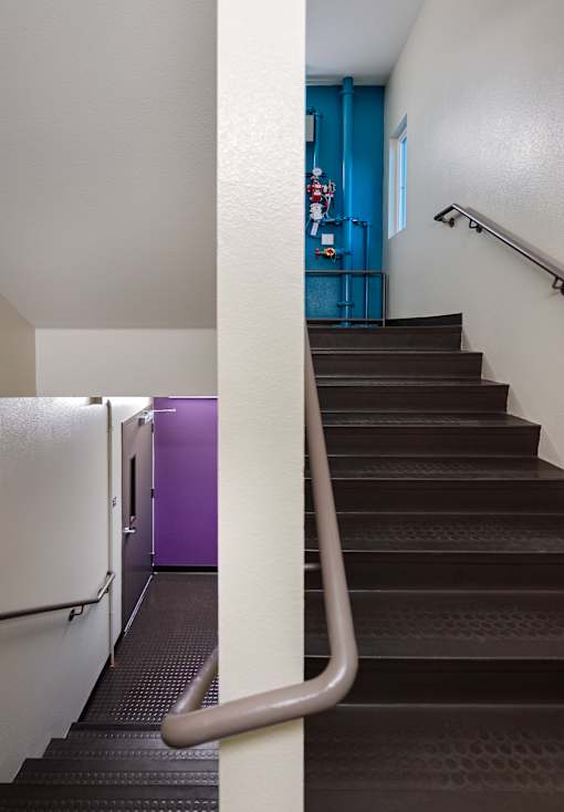 A staircase with a metal handrail and a purple wall in the background.