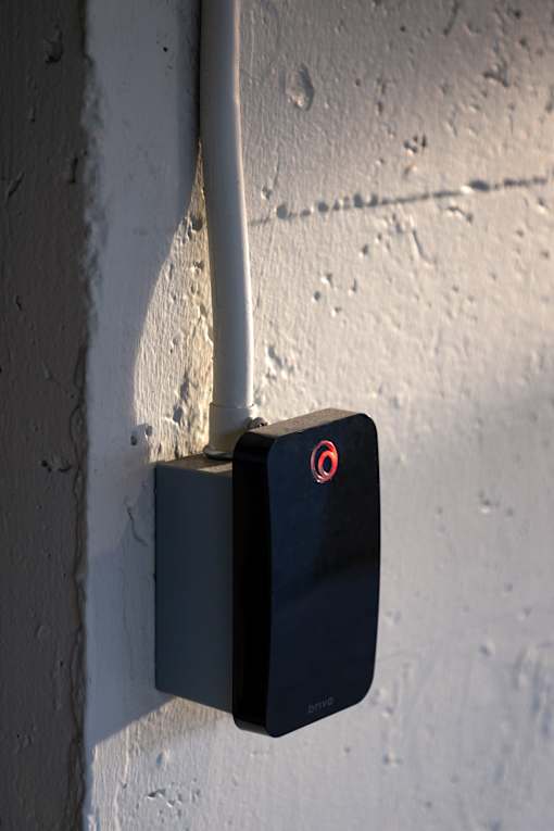 A black padlock with a red circle on the front is attached to a white pipe.