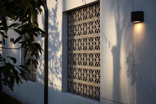 A wall with a patterned window and a light on.