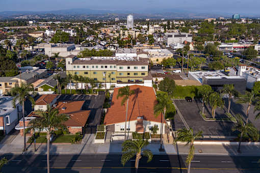 A view of a city from a high angle with buildings, palm trees, and a parking lot.