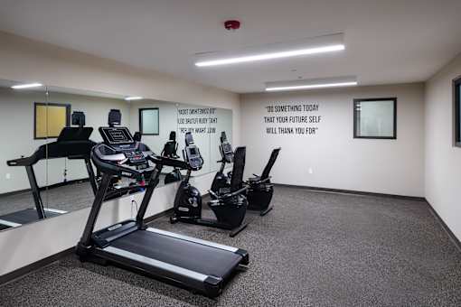 A gym room with treadmills and elliptical machines.