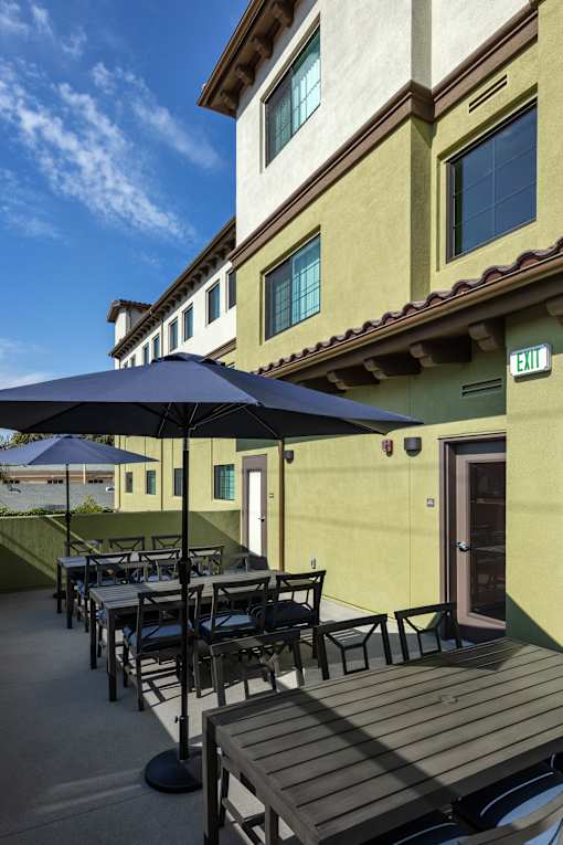 A patio with a table and chairs under an umbrella.