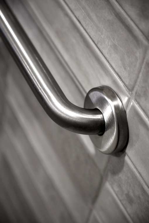 A close up of a stainless steel grab bar on a tiled wall.