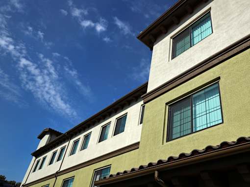 A building with a greenish-yellow facade and a blue sky with clouds in the background.