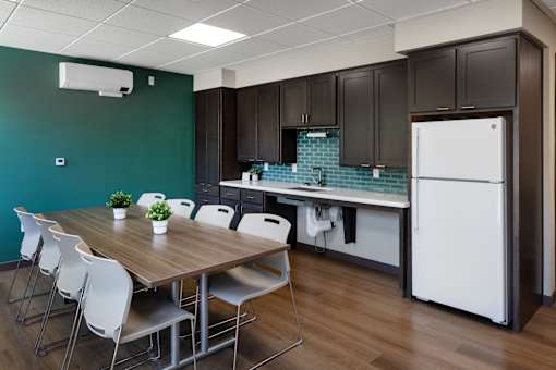 A kitchen with a table and chairs in front of a green wall.
