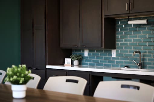 A kitchen with a table and chairs in front of a counter with a plant on it.