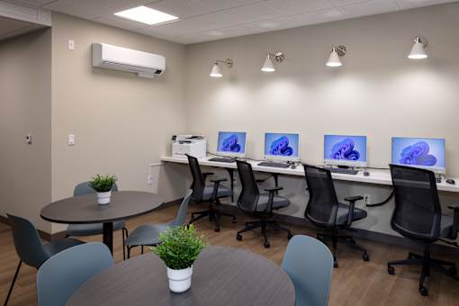 A room with a table, chairs, and computer monitors.