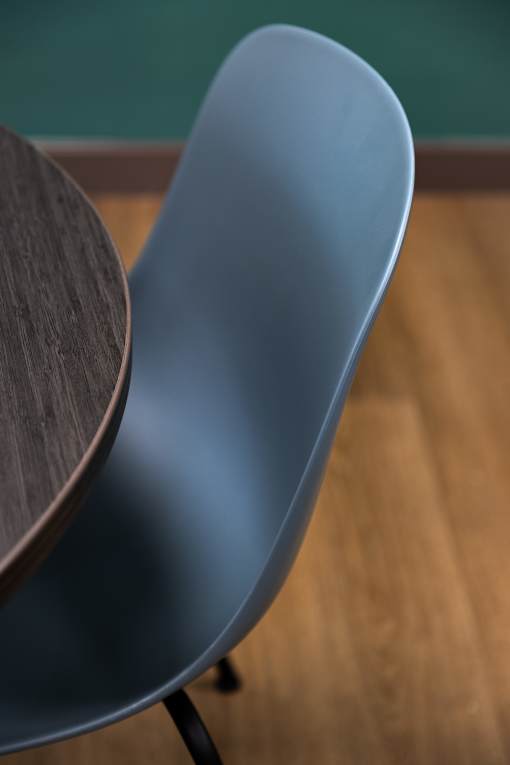 A blue chair with a wooden table in front of it.