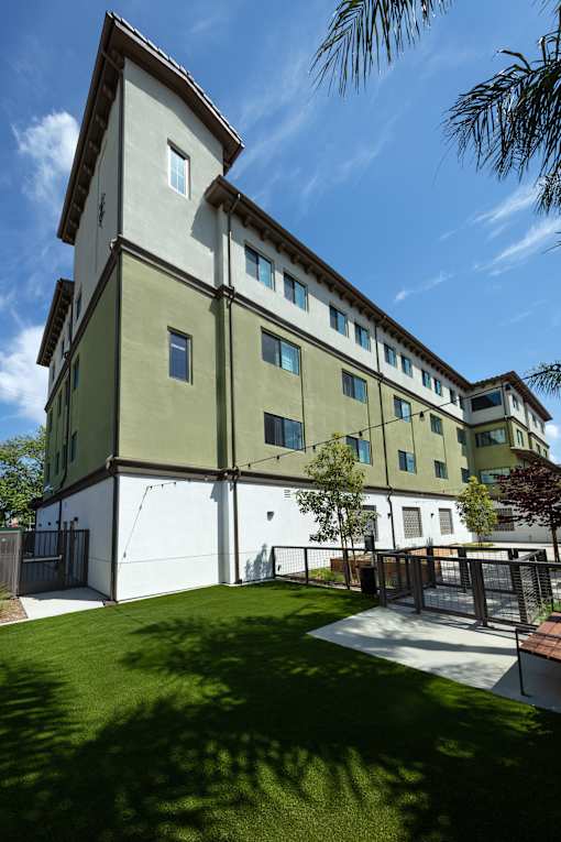 A modern building with a white and green exterior and a small courtyard in front.
