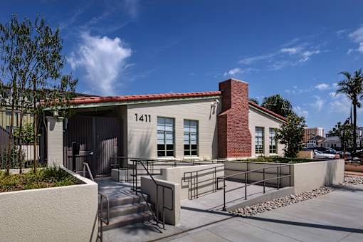 A modern building with a red brick chimney and a black gate in front.