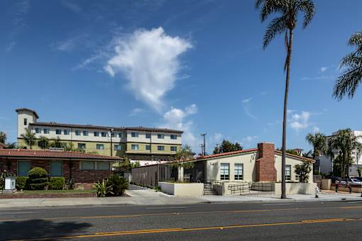 A building with a red roof and a white fence is in the foreground.