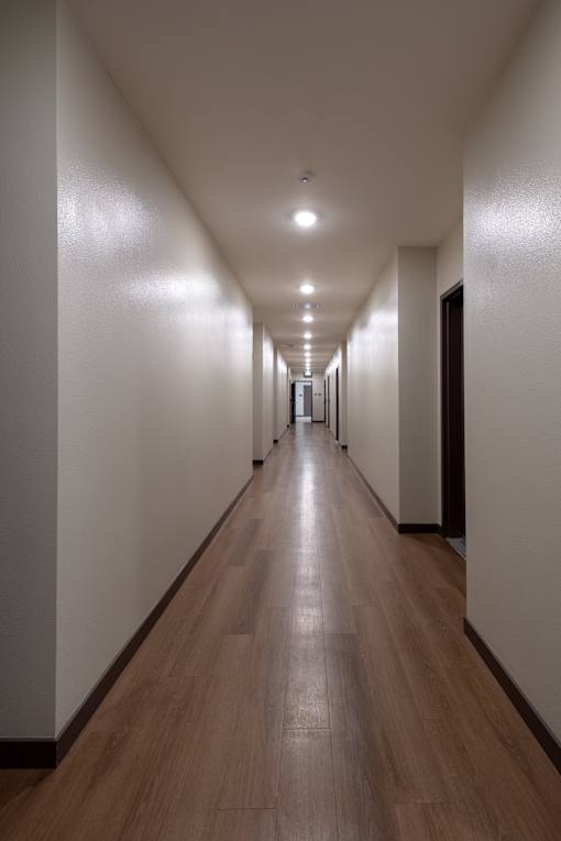 A long hallway with wooden floors and white walls.