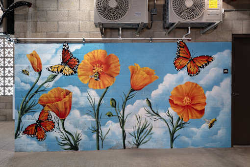 A mural of orange flowers and butterflies on a blue sky background.