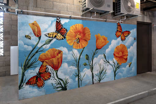 A mural of orange flowers and butterflies painted on a wall.