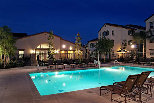 A swimming pool surrounded by lounge chairs and trees.